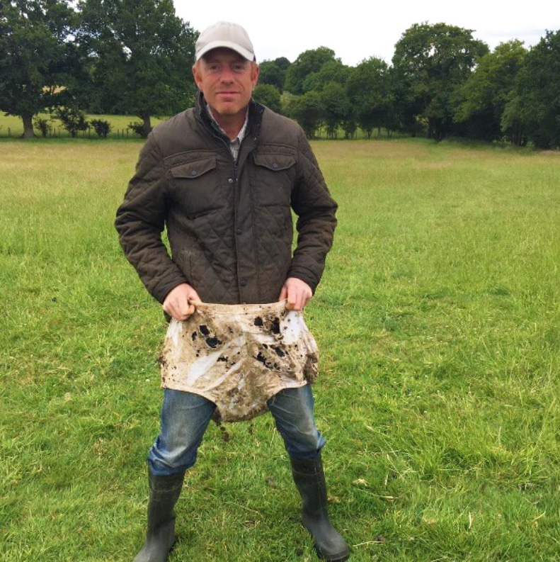 A farmer standing and holding up a pair of soiled underpants to demonstrate soil health in Kent farmland