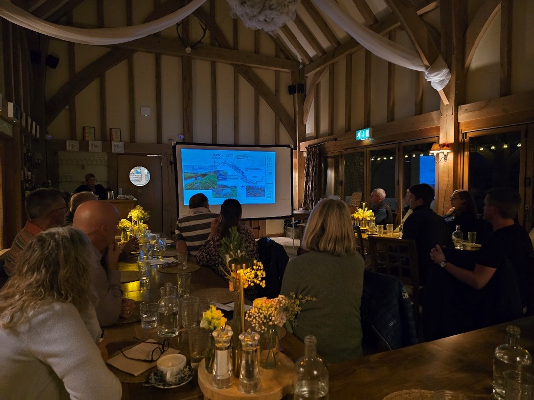 A barn room full of people watching a presentation.